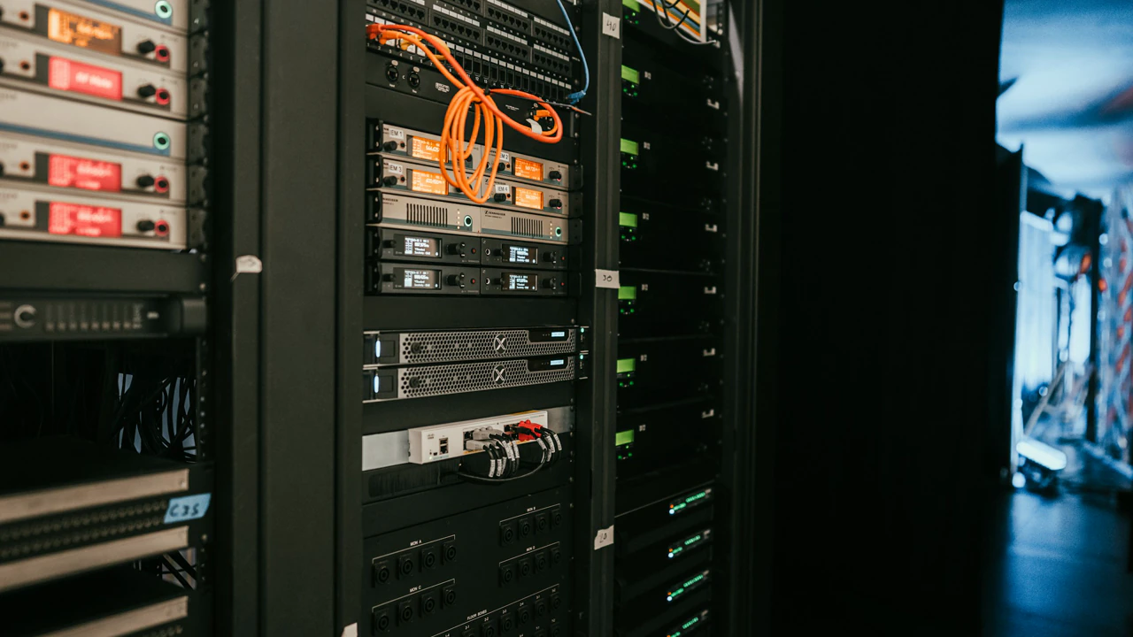 Racks of network equipment, cabled and labelled, in a dark room.