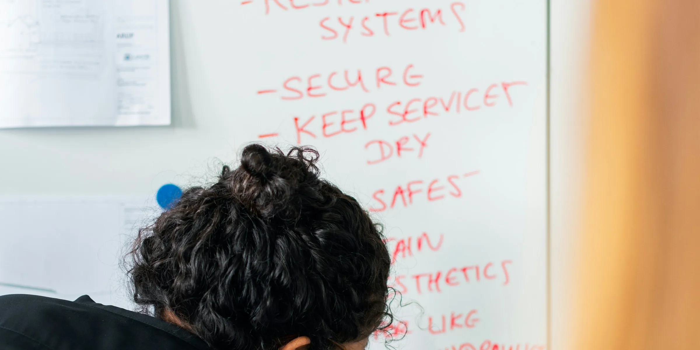 A whiteboard of handwritten security tasks, one person at work in front of it.