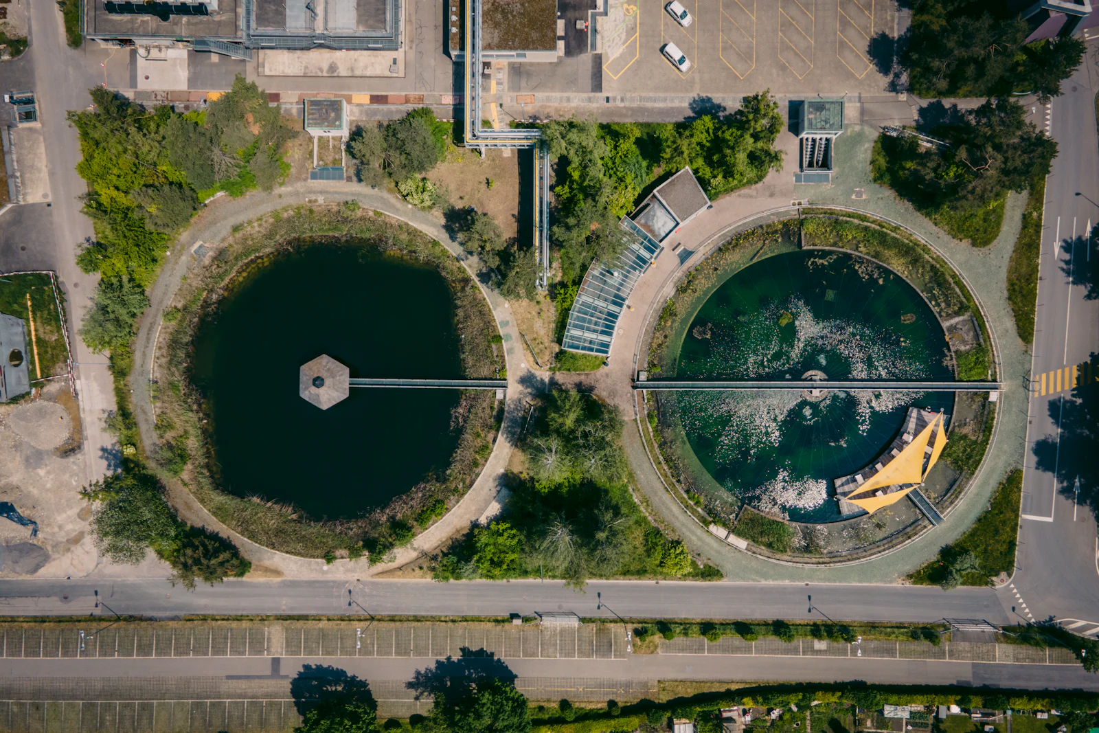 An aerial view of two circular water-treatment tanks among trees.